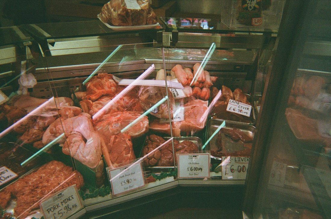Butcher counter with meat and handwritten signs